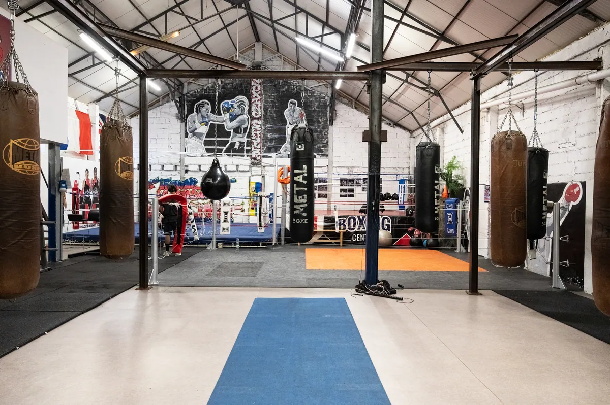 Frappe au sac lourd, garde haute et coudes serrés, mains bandées — Boxing Center, Toulouse.