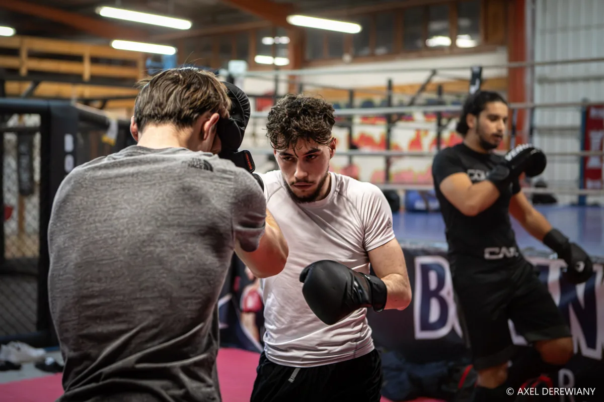 Cours de boxe anglaise : deux boxeurs gantés, garde haute, en round d'assaut devant le ring — Boxing Center, Toulouse.