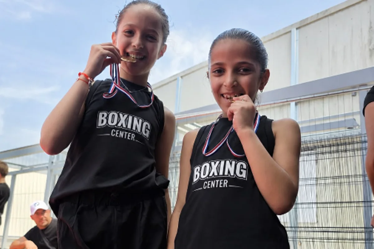 Deux jeunes boxeuses du club, médaille aux dents, en maillot Boxing Center après une compétition