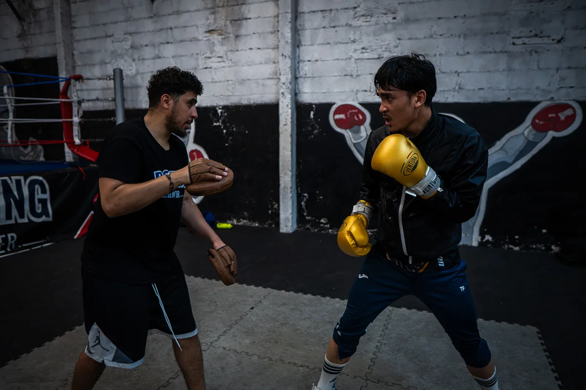 Travail technique aux pattes d'ours : le coach tient les cibles, le boxeur enchaîne direct et crochet — Boxing Center, Toulouse.